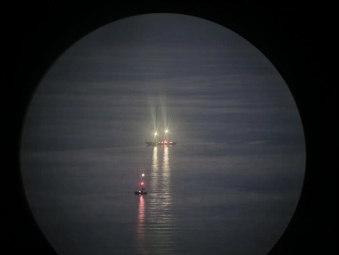 Dalekohledem loďky pozorující výbuchy sopky