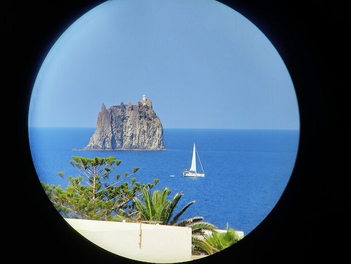 Dalekohledem skála Strombolicchio s majákem